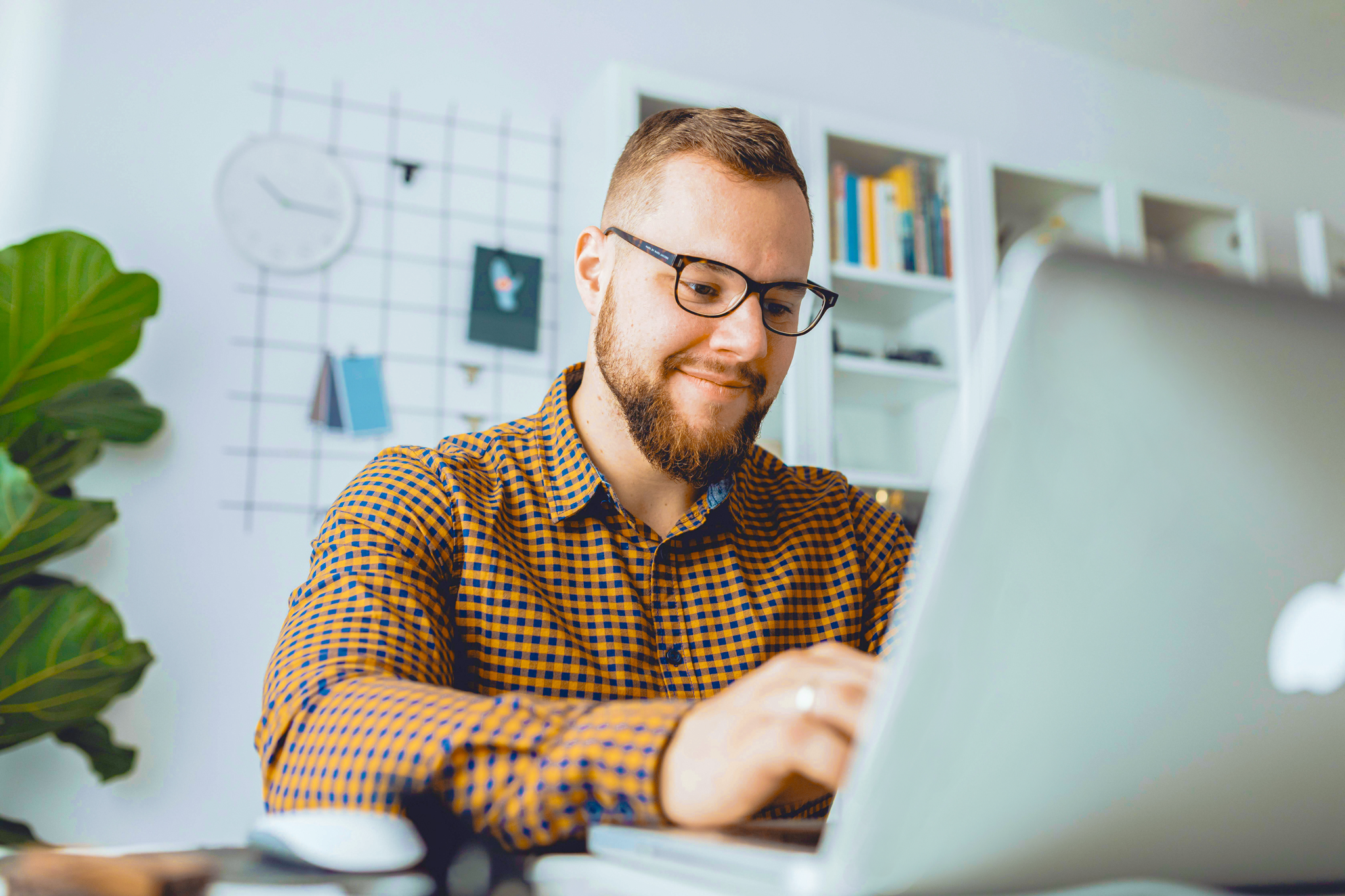 Mulher trabalhando remotamente, usando notebook e celular para contratar seguro empresarial, com agenda e materiais de escritório sobre a mesa