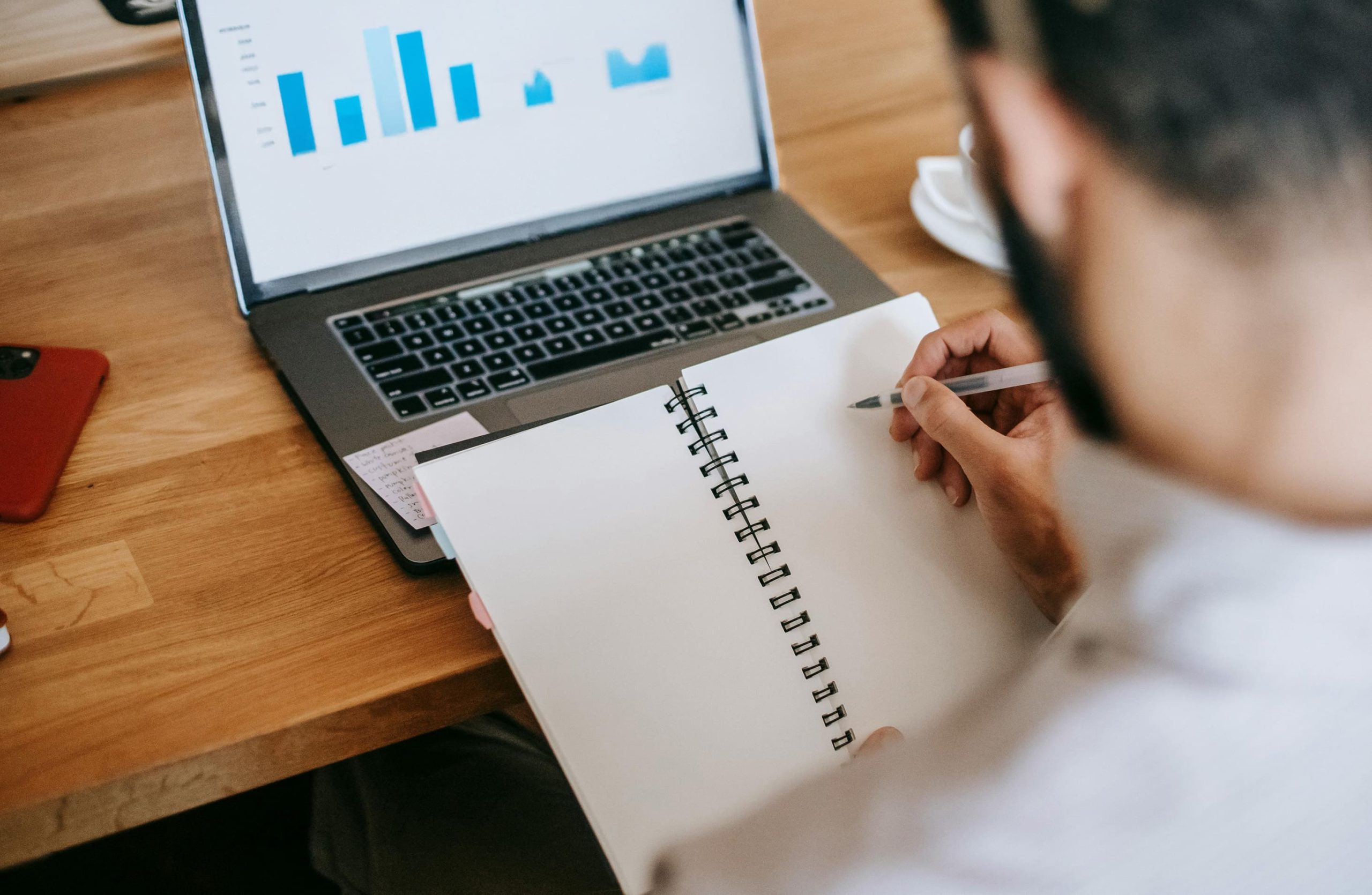 Profissional analisando gráficos e fazendo anotações enquanto pesquisa o melhor seguro empresarial para a empresa em que trabalha