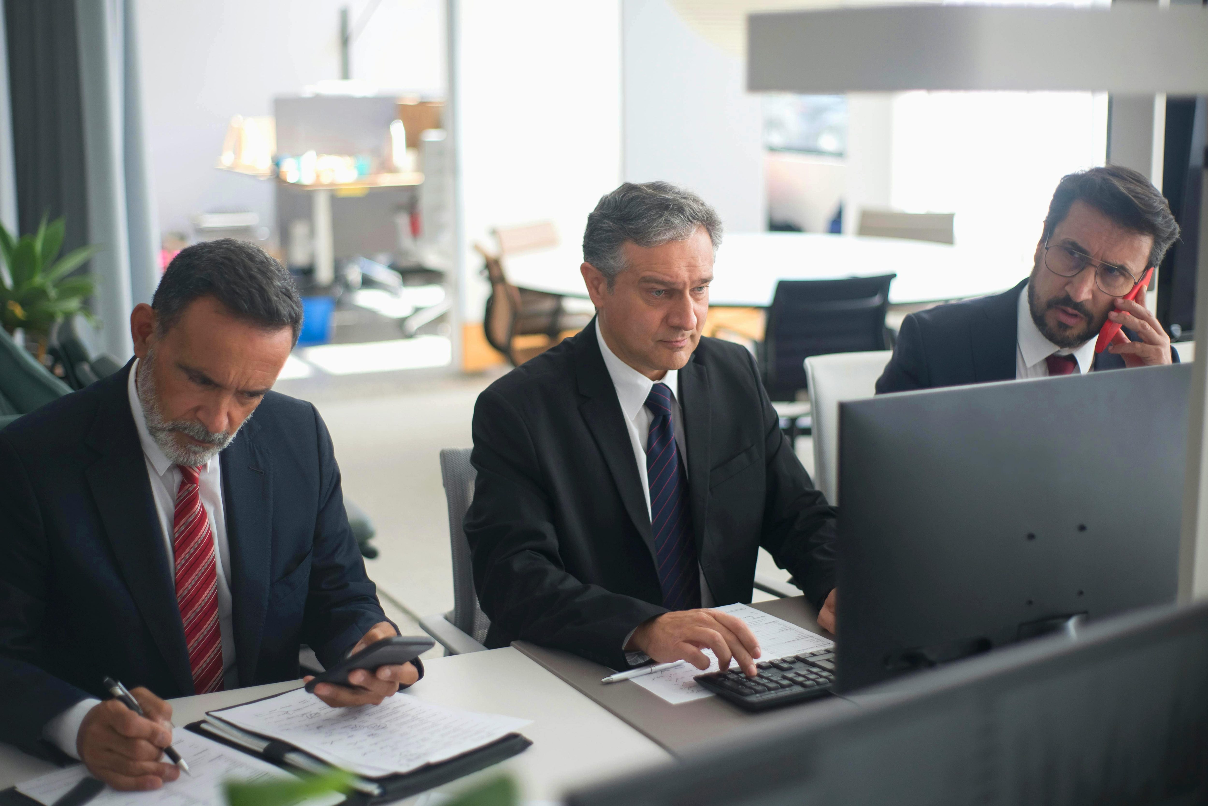 Três corretores de seguros experientes analisando dados em um ambiente corporativo, representando o papel estratégico do profissional na era do Open Finance.