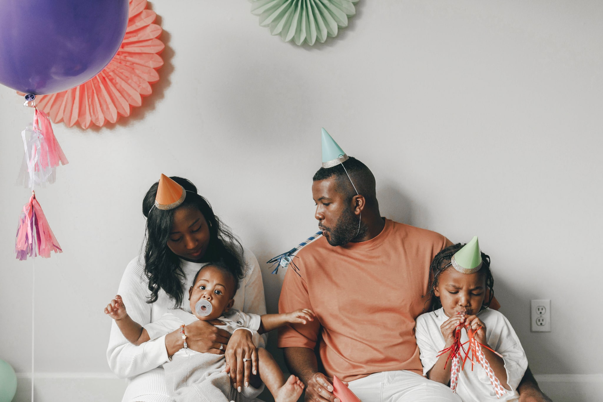 Família celebrando aniversário em casa com filhos pequenos, usando chapeuzinhos de festa