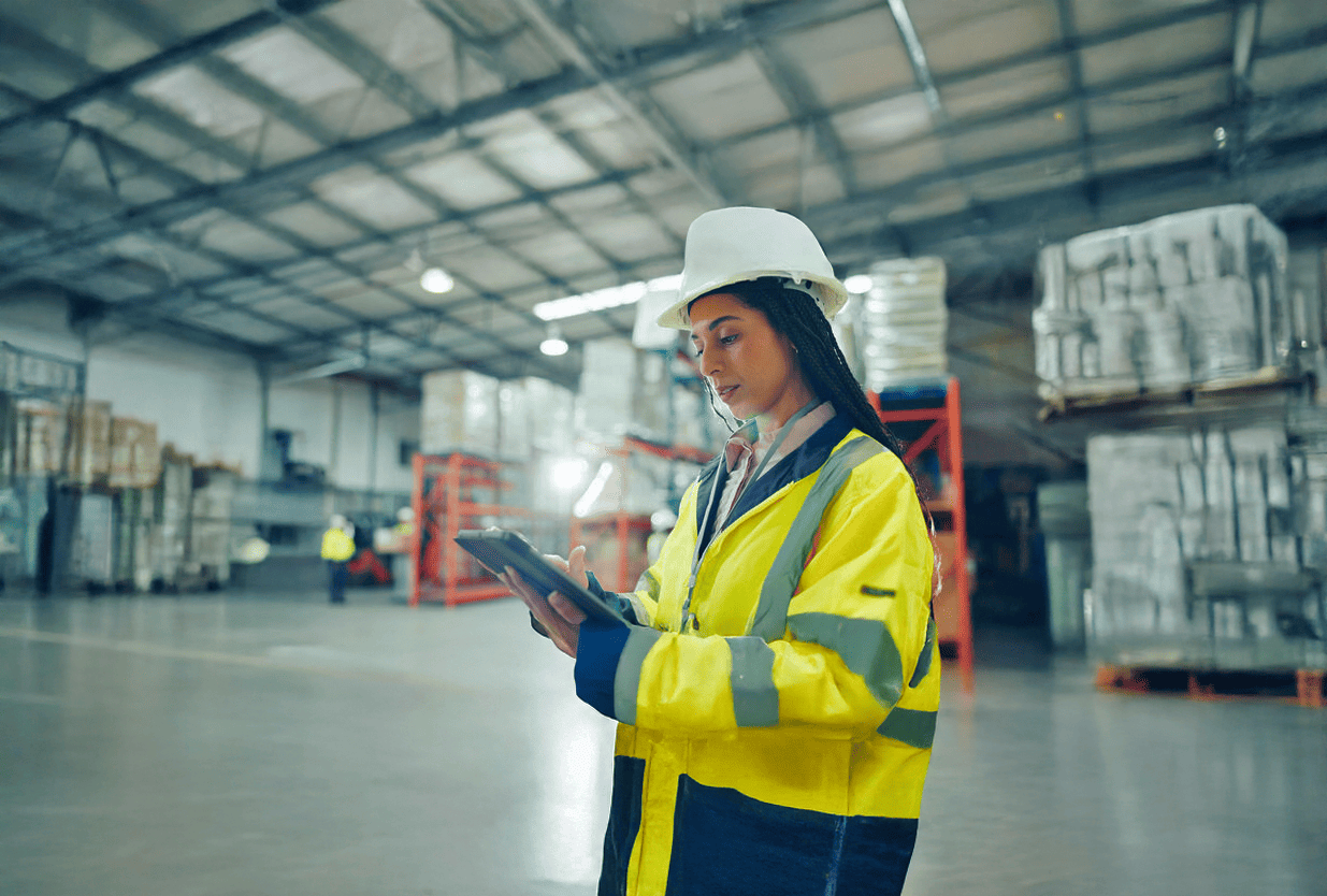 Profissional em ambiente industrial utilizando tablet para gestão operacional e análise de riscos